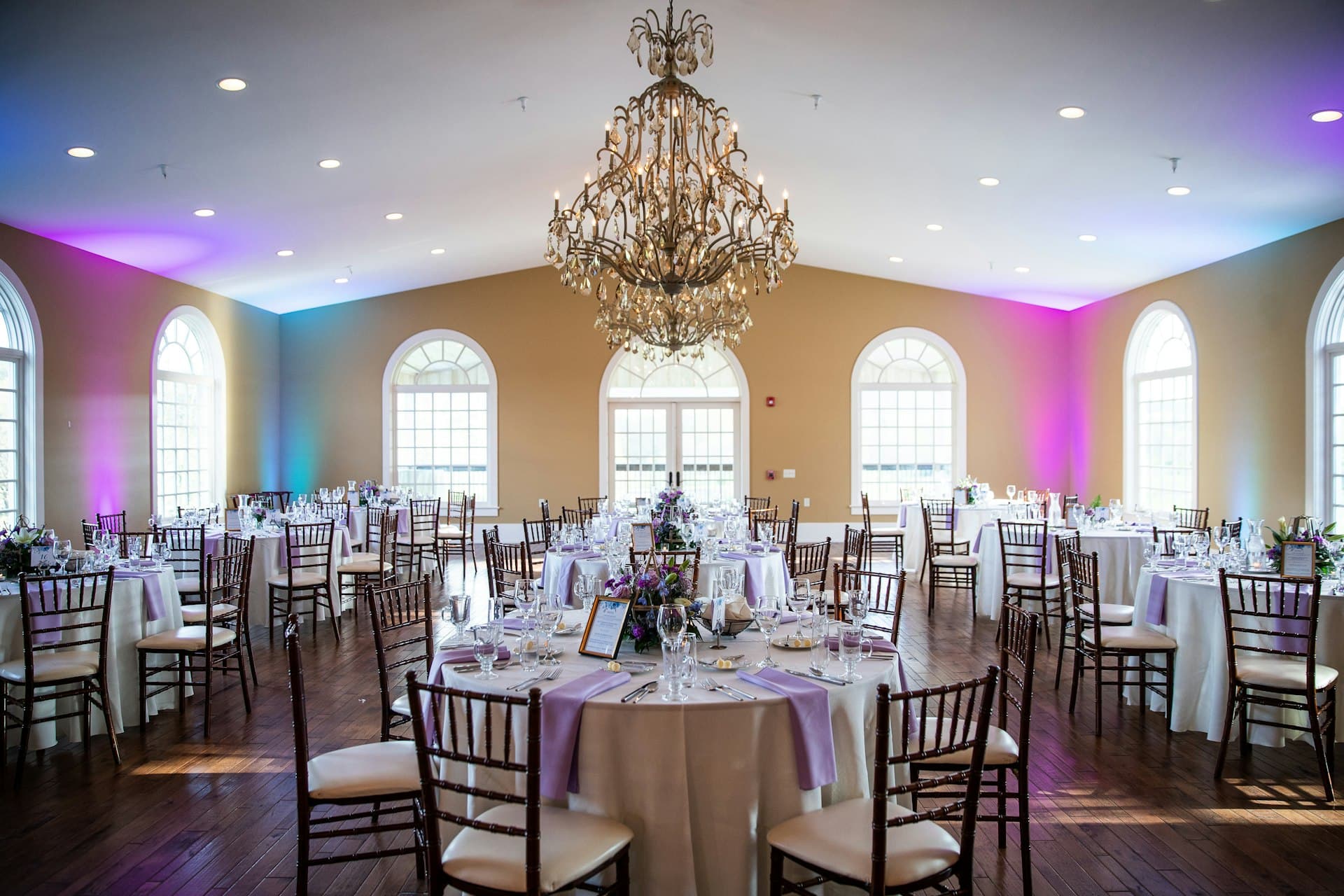 A crystal chandelier above a banquet hall set with round tables
